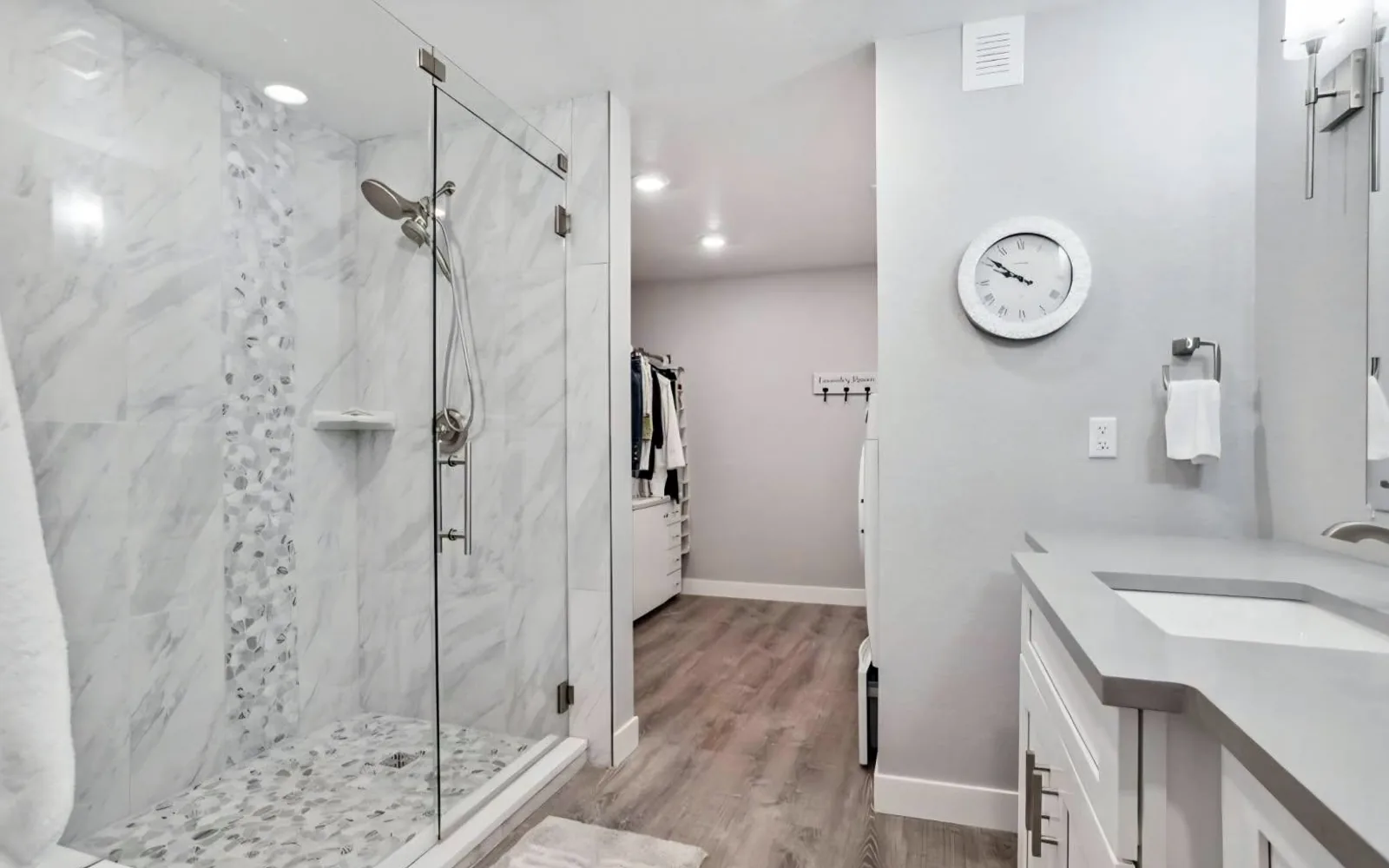Finished basement bathroom with a tiled walk-in glass shower, quartz vanity and walk-through closet